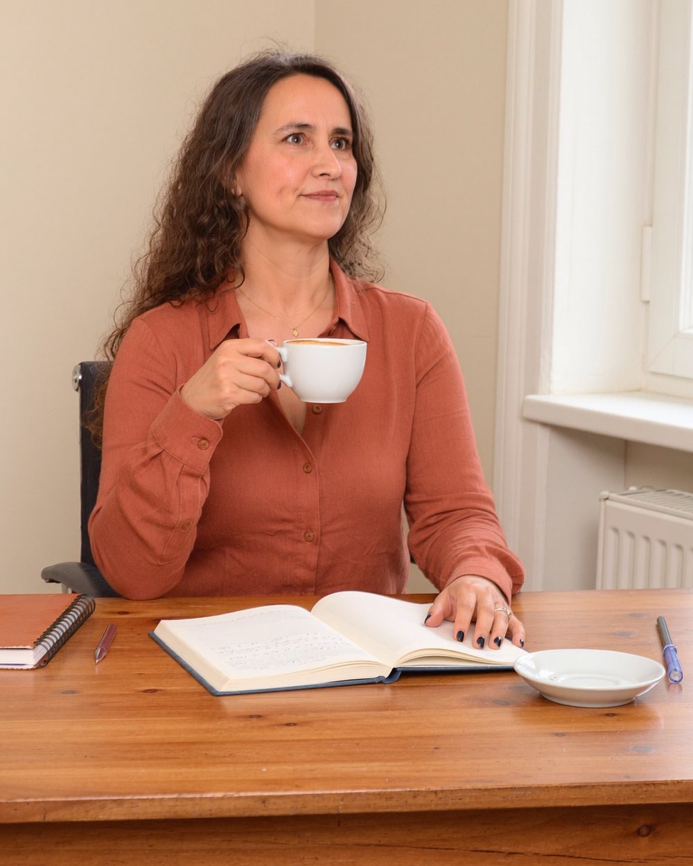 Gabriela Beale en su escritorio, con un café y su cuaderno abierto